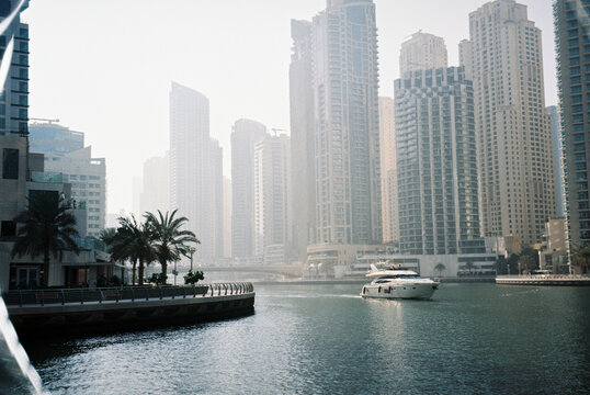 
Film Photo of Dubai Marina with Yacht and Skyscrapers in Hazy Light