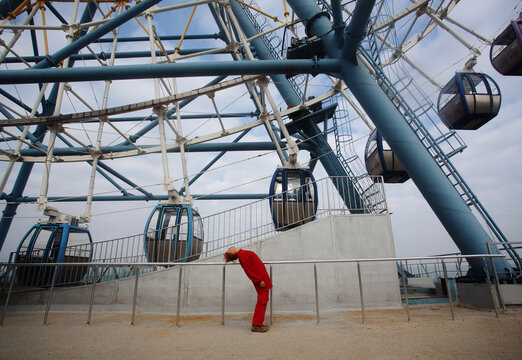 A woman in the red outfit in the front of the ferris wheel 