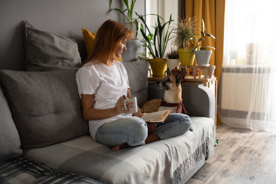 Female Reader with mug looking at dog. Woman and her best friend
