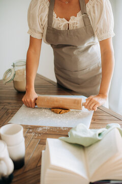 Woman rolling dough with wooden rolling pin at home