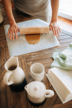 Anonymous woman rolling dough on wooden table