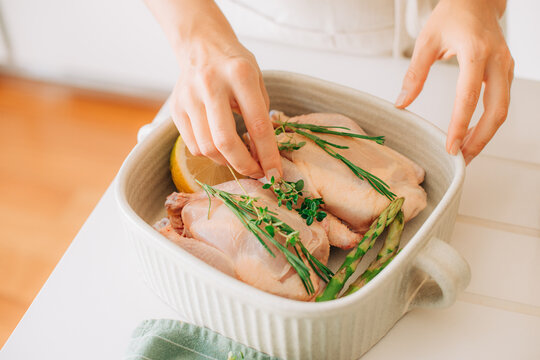 Raw chicken with herbs and asparagus in baking dish close-up