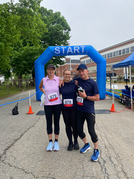 daughter and parents smiling at finish line after running 5k race
