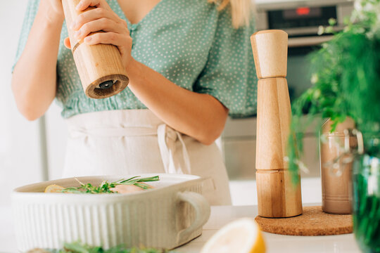 Close-up of pepper grinder seasoning raw chicken with herbs