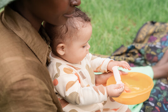 Baby eating in park while sitting on mom's laps 