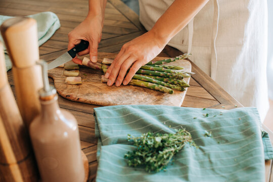 Female hands cutting asparagus on chopping board