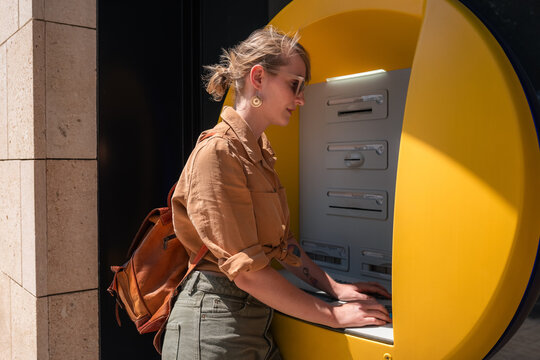 Woman Using an ATM in a City 