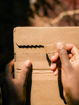 Woman is tearing off strip from cardboard box