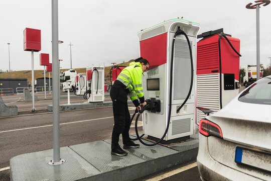 Technician Plugging In Electric Vehicle at Charging Station