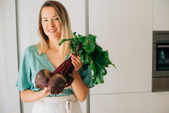 Close-up portrait of woman holding fresh beetroots with leaves