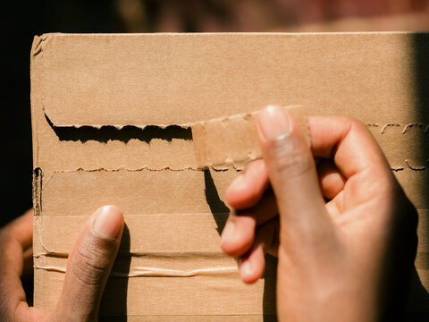Person Opening a Cardboard Box at Home on a Sunny Day