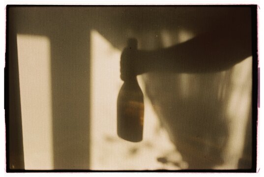 The shadow of a person's hand holding a bottle