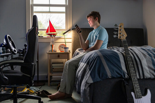 Teenager looking at cell phone bedroom dusk