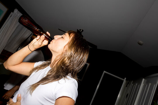 Woman drinking from bottle at home with direct flash