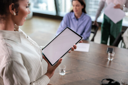 Businesswoman presents blank digital tablet at meeting.