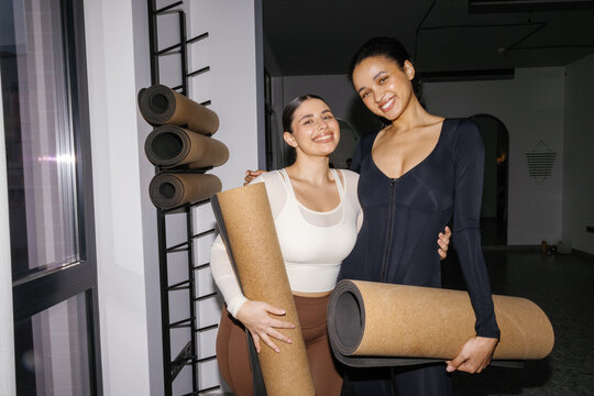 Portrait of young pleased girlfriends hugging and looking at camera
