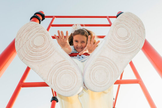 Low angle view of girl on climbing frame with feet in foreground