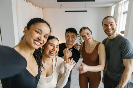 Portrait of five pleased people taking selfie in fitness studio