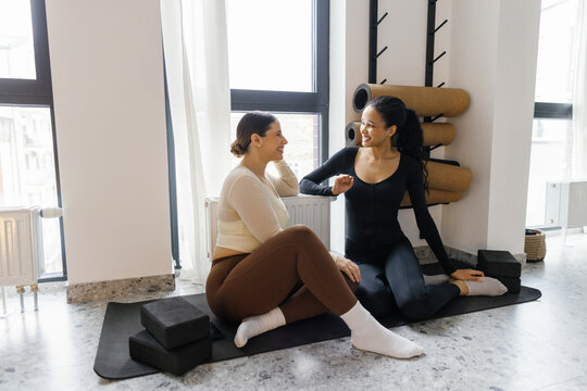 Pleased girlfriends spending time together in fitness studio
