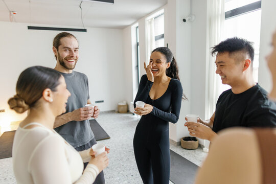 Multiracial group of people with cups of water laughing after training