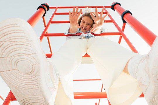 Low angle view of girl on climbing frame with feet in foreground