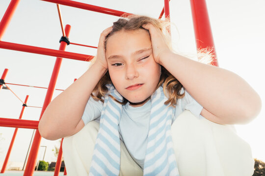 Girl holding head with intense expression in playground