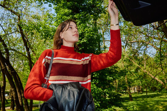 Woman closes car trunk outdoors