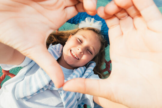 Girl reaching toward camera while lying on climbing net