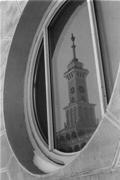 B&W Film Photo &ndash; Clock Tower Reflected in Oval Window