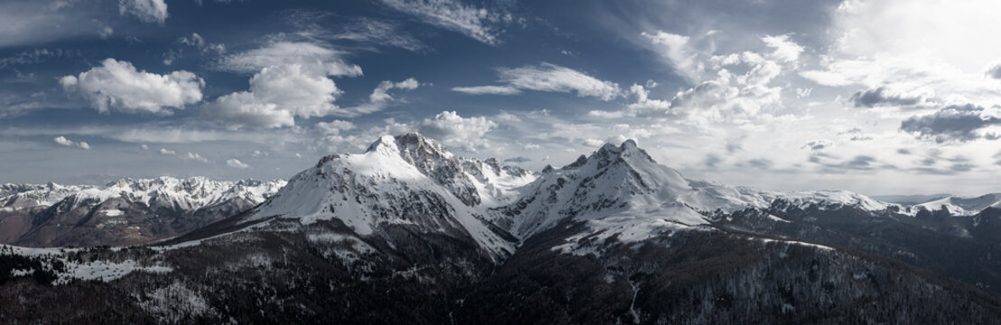 Snowy mountain twin peaks and blue sky with clouds, drone panorama