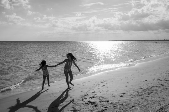 Children running freely along the seaside in black and white.