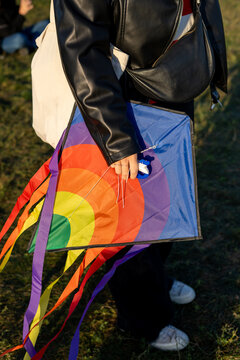 An anonymous woman holding a rainbow-colored kite