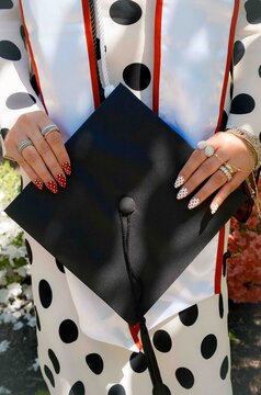 Manicured woman's hands holding graduation cap