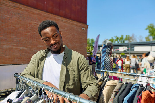 Man Browsing Clothes at Flea Market