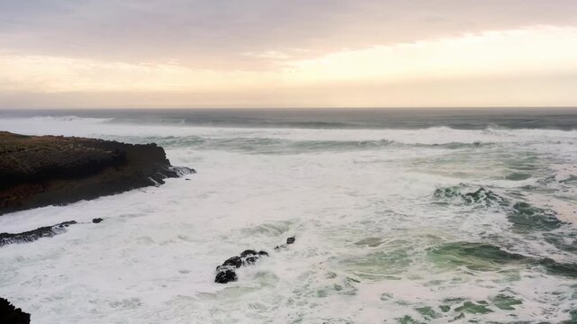 Nature reveals its power as waves crash against the rocks at Guincho Beach, casting a stunning display of water and light during a serene sunset stroll along the coast.