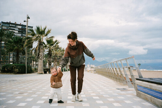 Young mother helps her child during a walk along the waterfront