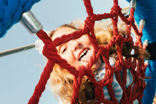 Girl looking through climbing net in playground