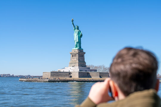 Tourist snaps a photo of  Statue of Liberty across the water
