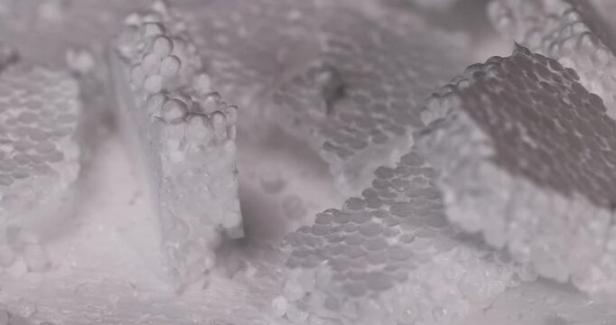 Light foam with protrusions, polymer foam in the form of matte white balls forms a stepped background of industrial material in the frame.