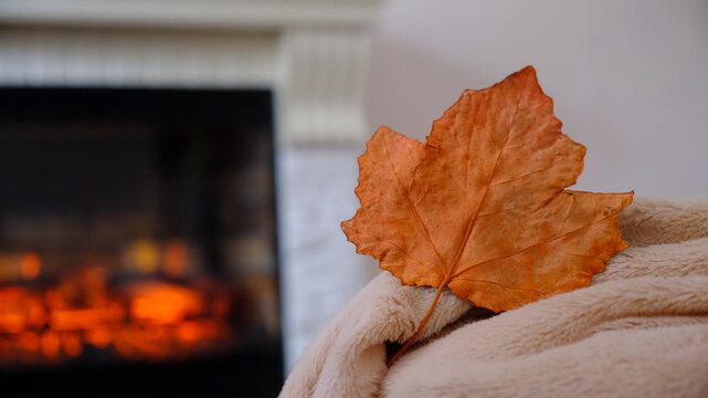 Fireplace and fluffy warm beige blanket. Autumn whispers through the window, while inside, warmth and comfort reign supreme. Snuggled under a soft, warm blanket by the crackling fireplace