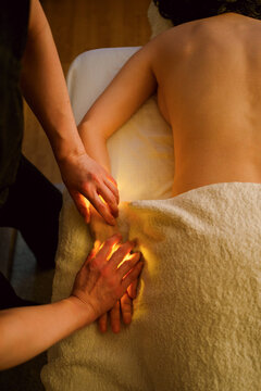 A massage therapist is giving a hand massage to a young woman