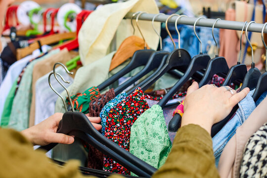 Vendor Arranging Clothes Rail at Market