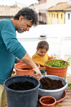 Father Preparing Soil While Baby Plays Nearby