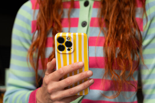 Woman Holds Phone While Wearing Colorful Clothes 