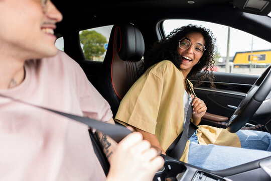 Young couple buckling seatbelts in car preparing for drive