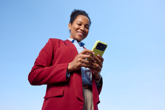 Formally dressed woman uses her phone against the clear sky