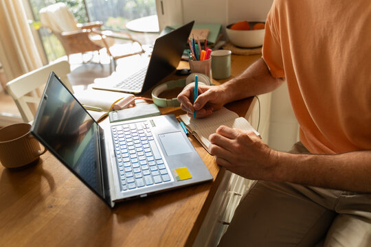 Man Working on Laptop and Writing Notes 