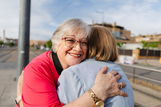 Smiling senior woman embracing friend showing affection