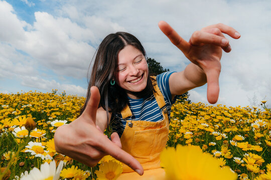 Girl Makes a Frame With Her Hands in a Flower Field on a Sunny Day