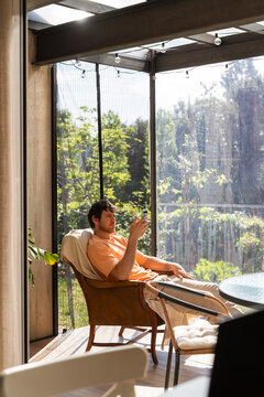Man Sitting on a Chair and Using  Phone sundeck 